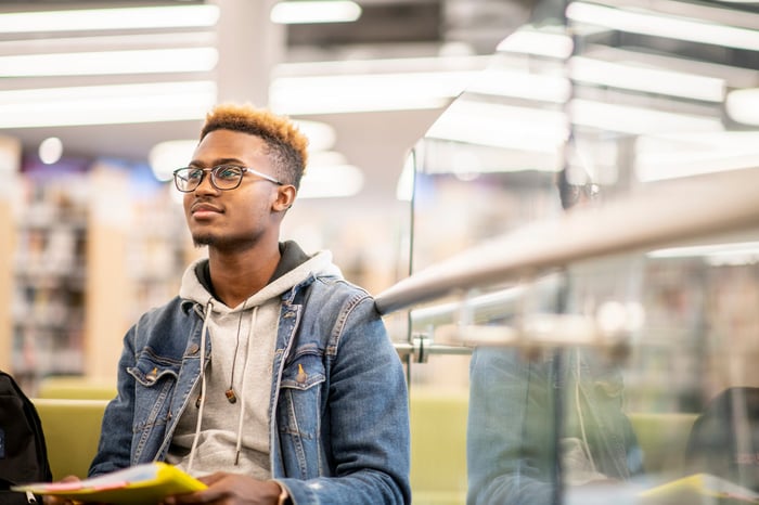 A person sits in a library and smiles.  